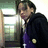 Pixelated static image of a person in dark clothing with purple accents, standing near a window or light source.