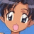 A pixelated anime-style character face with wide eyes and a pink tongue sticking out, next to stylized text on a black background.