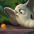 Animated cartoon character with large ears and a small horn, positioned on a wooden surface against green foliage background.