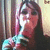 Pixelated static image of a person with long dark hair holding a light blue and white object against a blurred background.