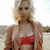 Pixelated static image of a person with light brown hair wearing red bikini top and beige cover-up, standing against bright background.