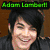 Green text 'Adam Lambert' above a pixelated image of a person with dark hair and a black jacket, next to three people holding pink heart-shaped objects.