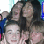 Three people with dark hair pose closely together in a pixelated image, one person's arm rests on another's shoulder.