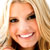 Static pixelated image of a smiling person with light brown hair and dark eyes, cropped to show upper face and shoulders against a blurred background.