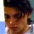 Pixelated close-up of a person's face with dark hair, brown skin tone, and visible eyes and nose against a blurred background.