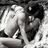 Black-and-white pixelated image of two figures in close physical contact, one with light-toned hair and the other with dark hair.