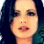 Pixelated close-up of a person's face with dark hair, light skin tone, and visible eyes nose mouth against a blue background.