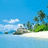 Pixelated beach scene with blue sky, white clouds, green foliage, and light-colored sand meeting calm water.