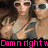 Two people wearing sunglasses pose closely together, with one person making a peace sign gesture and the other holding an object near their face.