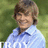 A pixelated image of a person in a light blue shirt against green foliage, next to bright green text on a solid blue background.