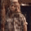 A pixelated figure in a light-colored outfit with a hat, standing against a dark background with a metallic bar visible.