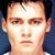 Pixelated close-up of a person's face with light skin, brown eyes, and dark hair against a dark blue background.