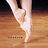 A ballet dancer's feet in white pointe shoes on a wooden floor, with pink pixelated text 'love to dance' on a yellow background.