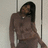 Pixelated image of a person with long dark hair wearing a brown patterned top against a light background with vertical lines.
