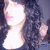 A person with curly dark hair and light skin appears in a of four showing slight head movement against a dark background