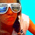 A person wearing white sunglasses and a light-colored sleeveless top with dark accents against a bright blue background.