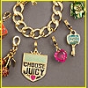 A gold chain bracelet with multiple charms including a shield-shaped pendant reading 'CHOOSE JUICY' and a small pink gemstone.