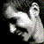 Animated sequence showing two figures with distinct facial features and clothing, one holding a camera-like object, against a dark background with pixelated details.