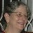 Static pixelated image of a person's face with blurred features, set against a dark background with light vertical elements.