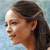 Pixelated profile view of a person with dark hair tied back, light skin, and a neutral expression against a light blue background.