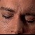 A pixelated close-up of a person's face showing closed eyes, a visible eyebrow, and a small mole on the cheek.
