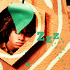 A person with curly brown hair partially covered by a green leaf, surrounded by orange and white striped patterns with "Zzz" text and small green hearts.