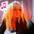 A blonde woman with long hair wears a dark jacket over a blue top, positioned against a pinkish background with a pink musical note symbol in the top-left corner.