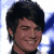 A pixelated image of a person with dark hair and light skin, smiling against a bright background.