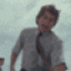 A person in a light gray shirt and dark tie performs a sequence of animated movements against a cloudy sky background.