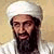 A pixelated image of a person wearing a white turban and white clothing, with a long dark beard, against a light brown background.