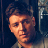 Static pixelated image of a person's face with visible hair and partial shoulder, set against dark background with light vertical elements on the right.
