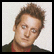 A pixelated image of a person with brown hair and a red shirt on the left, next to green text reading "HE'S WATCHING YOU!" on a black background.