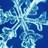 A pixelated static image of a snowflake with blue and white tones, featuring six symmetrical arms extending from a central point against a dark blue background.