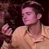 A person in a yellow striped shirt holds an object while transitioning from closed eyes to open eyes