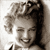 Static grayscale pixel art of a smiling woman with styled hair, cropped to show upper face and shoulders against light background.