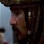Pixelated still image of a person in profile wearing a dark hat, with a light blue background on the left side.