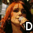 A person with long red hair wearing a black crop top and camouflage pants holds a microphone, partially obscured by large white letters D, U, L.