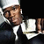 Pixelated image of a person wearing a white chef's hat and dark jacket with white shirt, cropped to show upper body against black background.