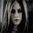 Pixelated static image of a person with long dark hair and light-colored streaks, wearing dark eye makeup, against a dark background with vertical light and dark stripes.