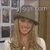 A woman with long blonde hair wears a gray hat, white crop top, and yellow skirt in a static image.
