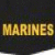 Static pixelated image of the word "MARINES" in bold, golden-yellow capital letters against a dark background with subtle green and blue tones.