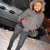 A person in a gray hoodie with pink accents stands beside a dark vehicle on a snowy surface, captured across showing subtle pose shifts