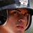Pixelated close-up of a person wearing a dark cap with light-colored brim, showing partial face and neck against blurred background.
