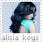 Alicia Keys in profile view wearing a turquoise sleeveless top with long dark hair against a light blue background.