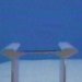Static 75x75 pixel buddy icon showing two white table-like structures with brown tops against a blue background, rendered in low-resolution pixels with visible dithering and color banding.