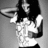 Pixelated grayscale image of a person with long dark hair wearing a white sleeveless top, holding an object near their face.