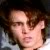 Pixelated close-up of a person's face with brown hair, light skin, and a neutral expression against a dark background.