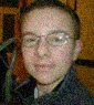 A person with short dark hair and glasses appears in three showing subtle facial expression changes against a wooden background