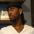 A person in a white V-neck shirt and dark cap appears across four with slight head position changes against a shelf background