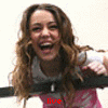 A woman with long wavy brown hair wearing a white and pink top, holding a black bar, with red text below her changing from 'live' to 'laugh' to 'love'.
